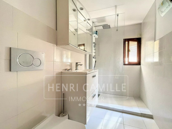 Salle de douche moderne avec carrelage blanc et meuble vasque.