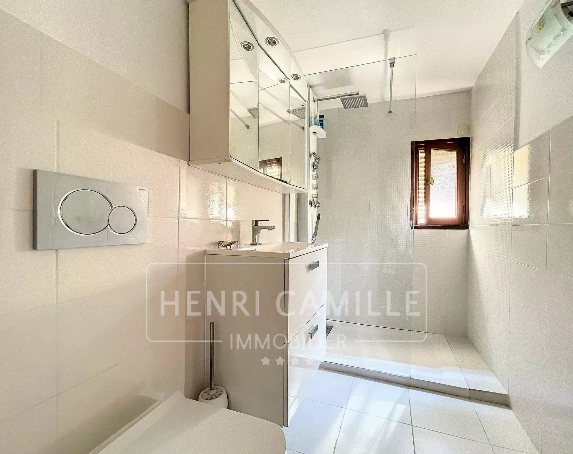 Salle de douche moderne avec carrelage blanc et meuble vasque.
