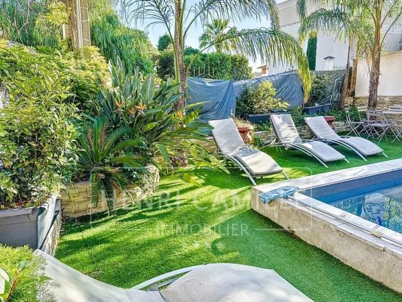 Jardin avec piscine et chaises longues dans une maison à Cannes.