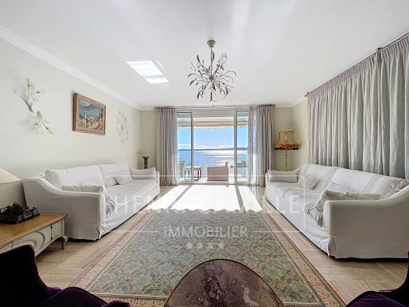 Salon lumineux avec vue sur la mer à Cannes, grandes fenêtres et décoration élégante.