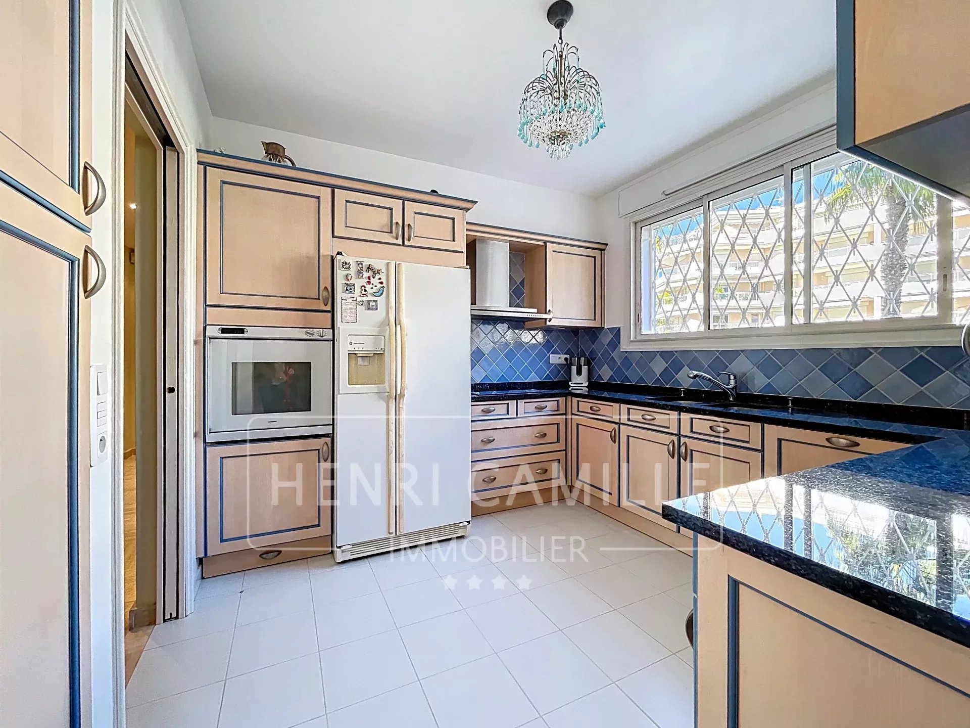 Cuisine équipée d'un appartement à Cannes avec meubles en bois et plan de travail en granit.