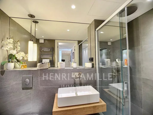 Modern bathroom with walk-in shower and washbasin on wooden unit.