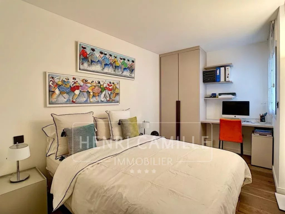 Bedroom in a renovated apartment in Cannes with a desk and colorful artwork on the wall.