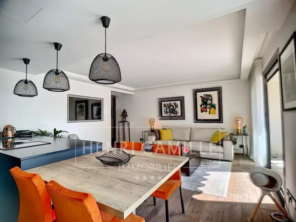 Interior of a renovated apartment in Cannes with living room, open kitchen and dining table.