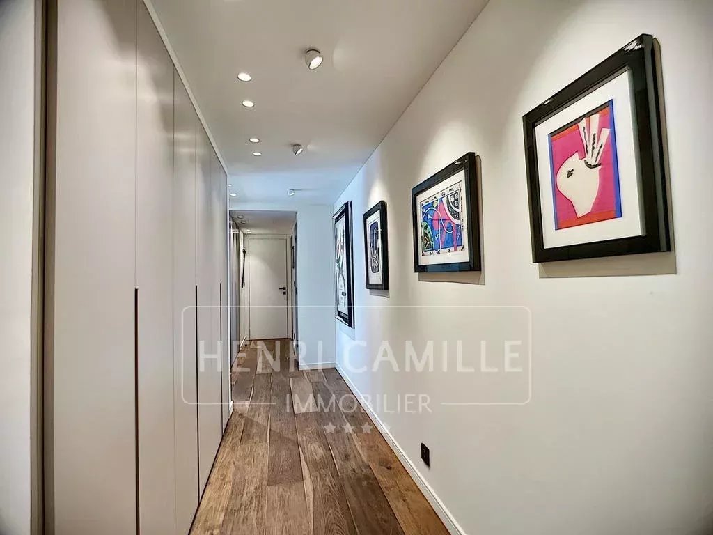 Hallway of an apartment in Cannes Hallway of a renovated apartment with artwork on the walls and a wooden floor.