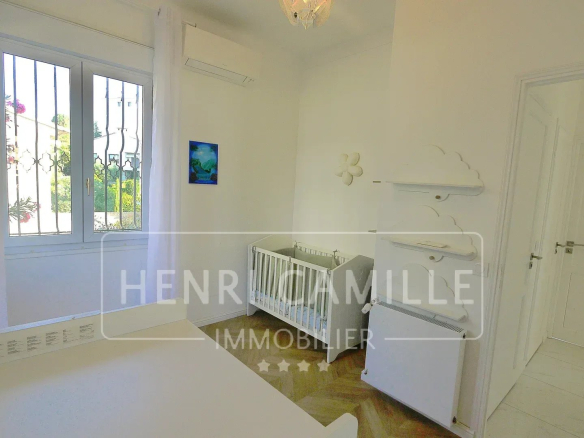 Bright room with a baby cot and storage furniture, windows overlooking the outside.