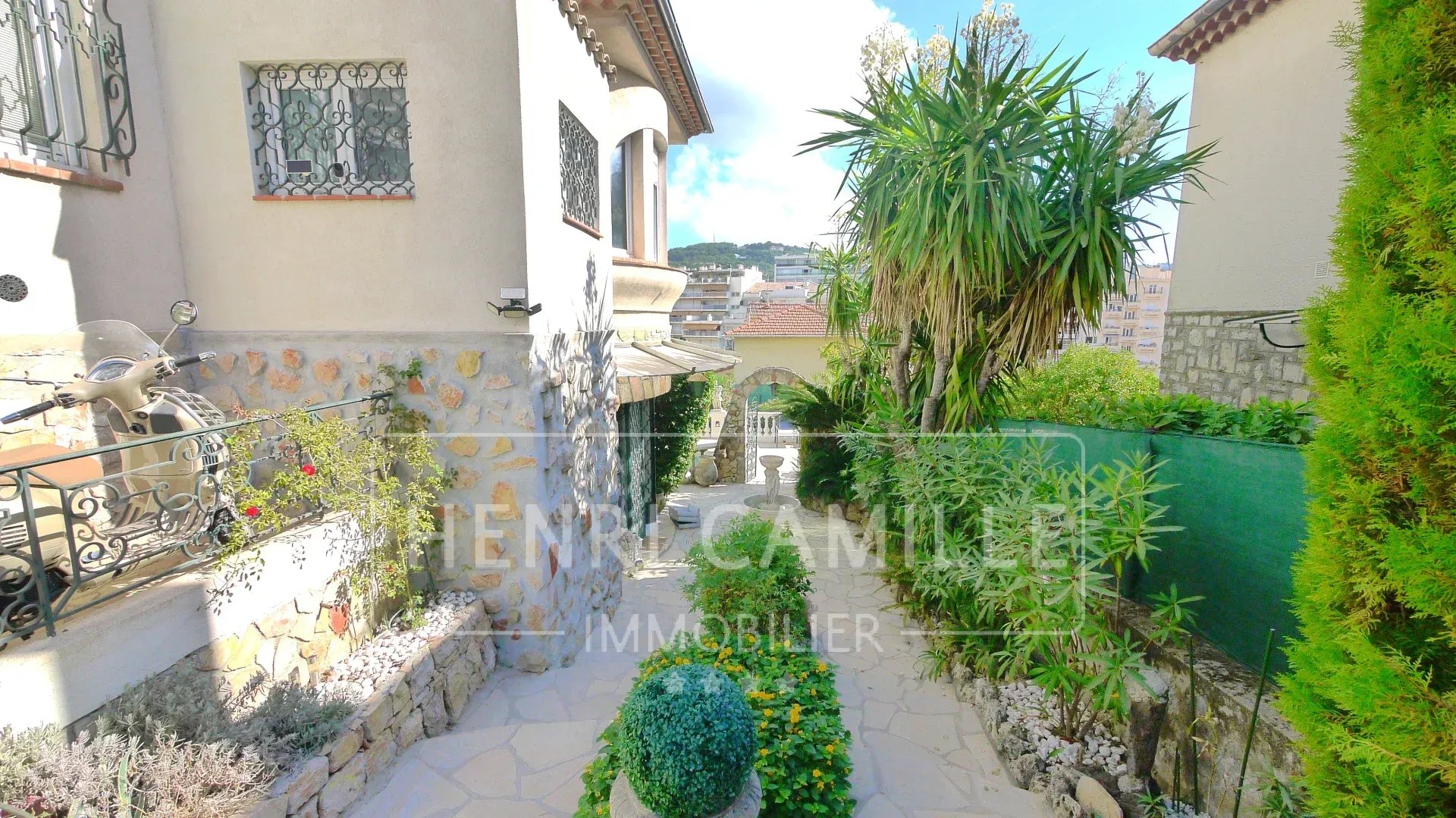 Driveway leading to a villa in Cannes Petit Juas, with garden and plants.