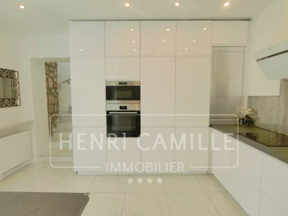 Modern and bright kitchen of a villa in Cannes Petit Juas with white furniture and integrated appliances.