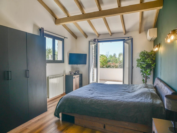 Bedroom with dark green feature wall, exposed wooden beams, and a low platform bed facing a balcony door.