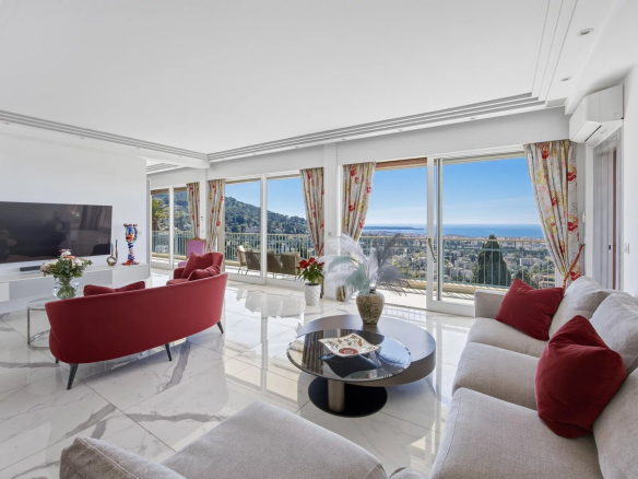 Bright living room with marble floors, red sofa and chairs, and large windows showing an ocean view.