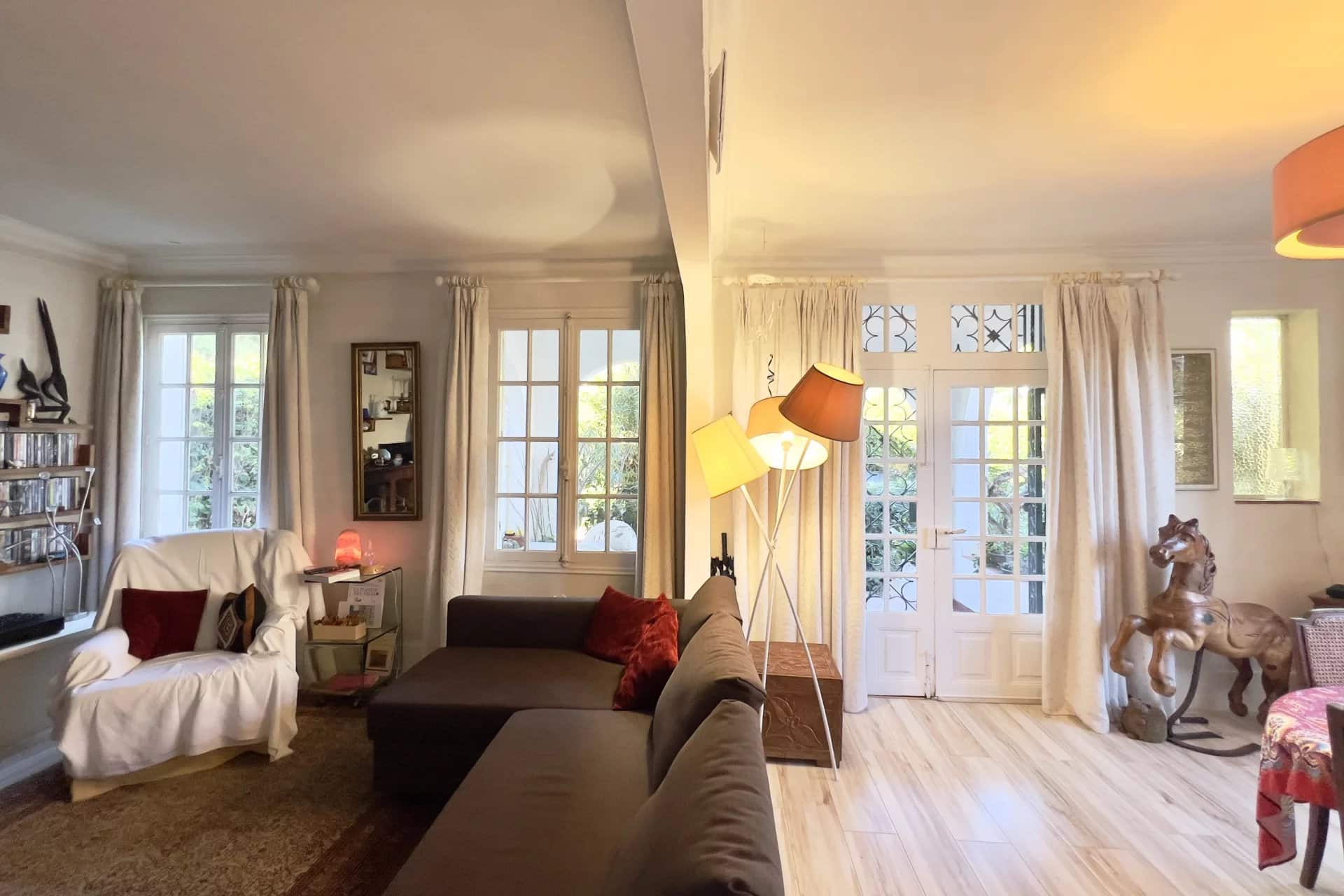 Interior of a villa in Cap d'Antibes with a bright living room and windows opening onto the outside.