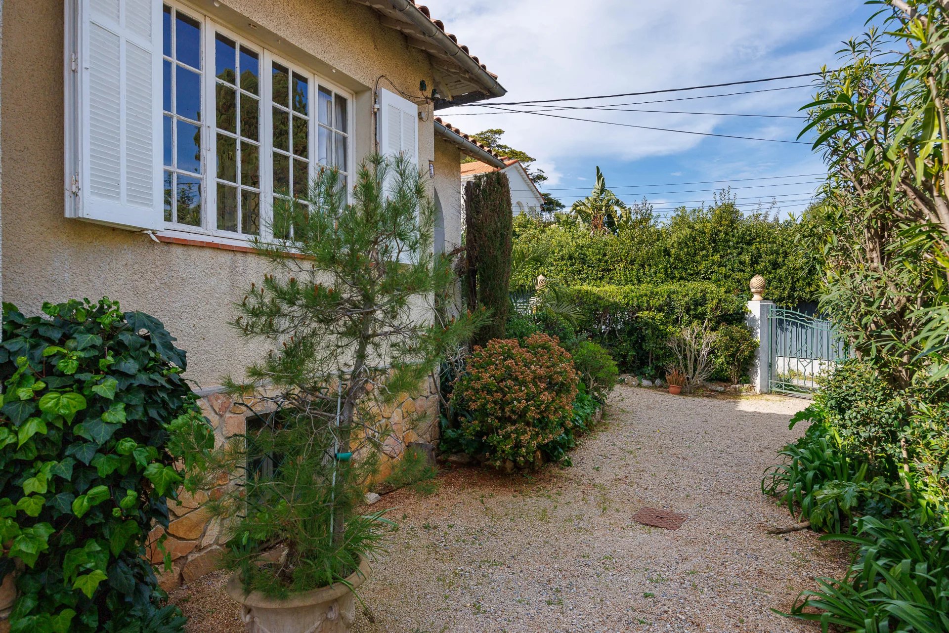 Entrance to a villa with a garden in Cap d'Antibes, surrounded by greenery.