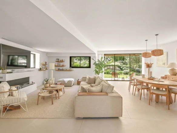 Interior of a modern villa with bright living room and dining room, garden view.