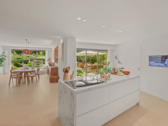 Interior of a modern villa with an open-plan kitchen leading to a bright living room and access to the garden.