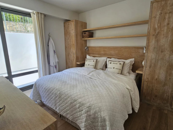 Room in a bright apartment with double bed and wooden furniture, overlooking a garden.