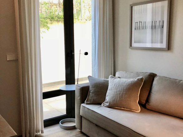 Interior of an apartment with a sofa and curtains, overlooking an outdoor garden.