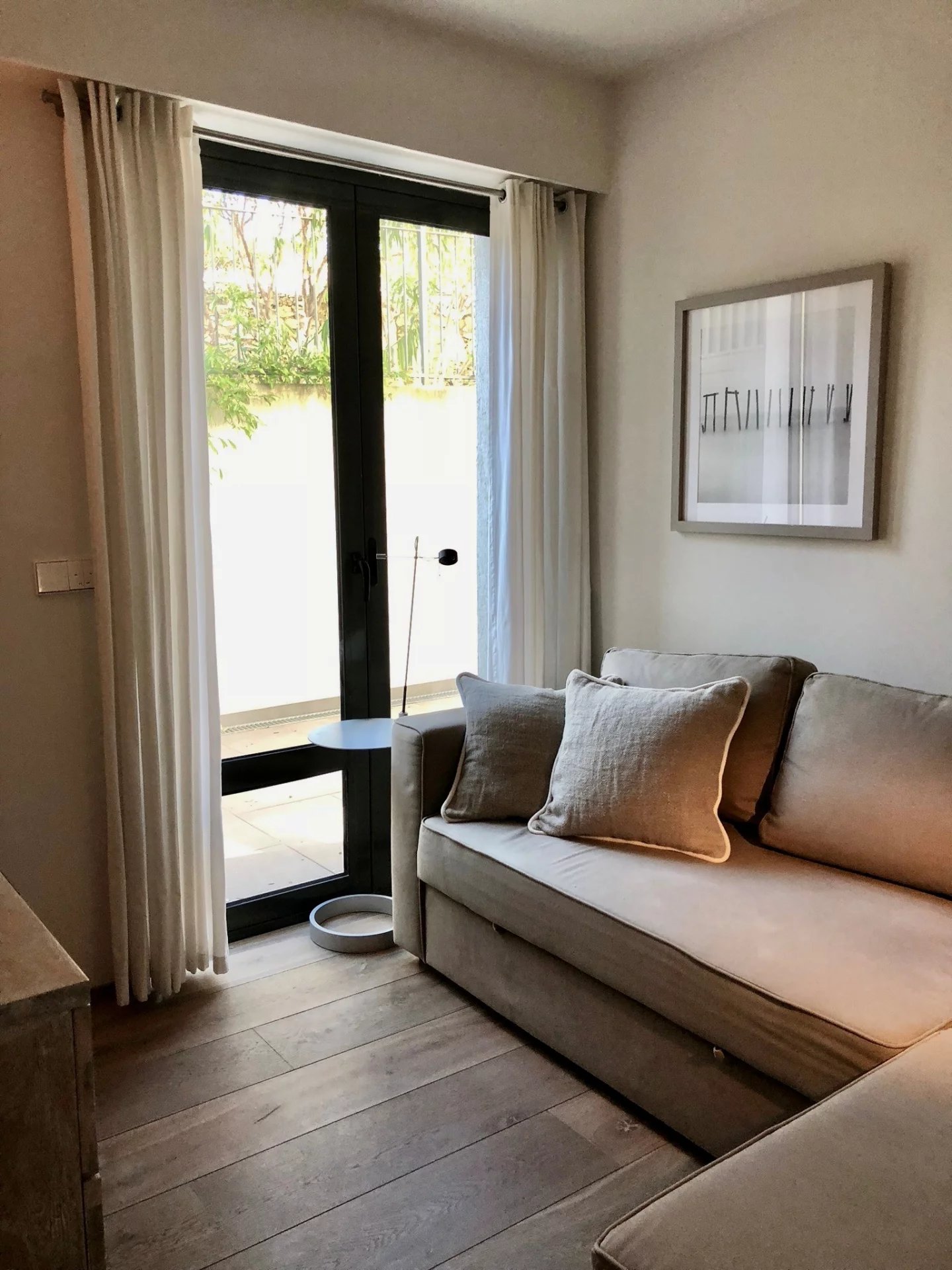 Interior of the apartment in Cap d'Antibes Interior of an apartment with a sofa and curtains, overlooking an outdoor garden.