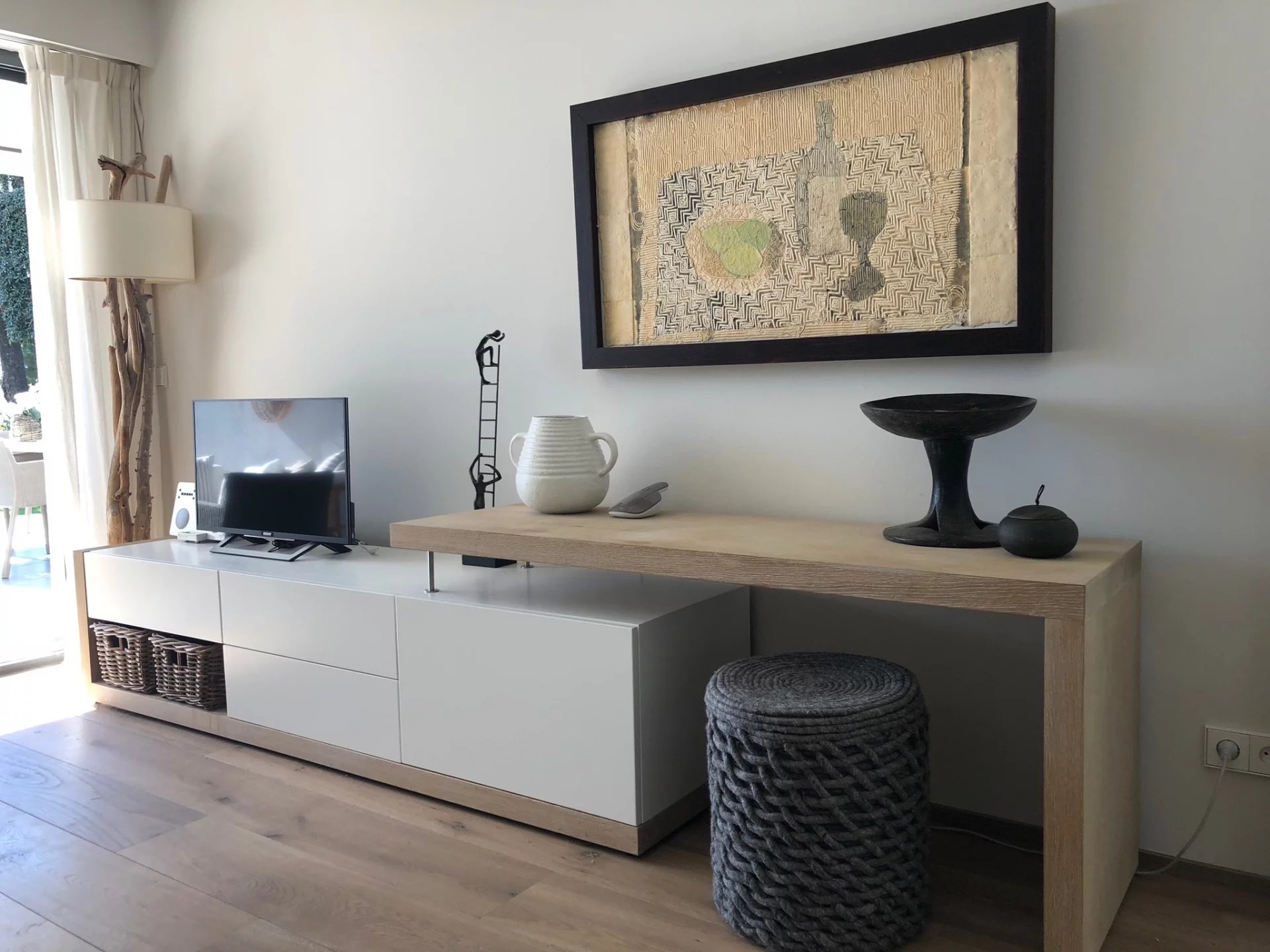 Living room of an apartment in Antibes Interior of a modern living room with wooden furniture, television and artistic decoration.