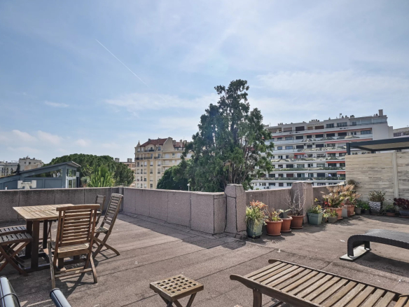 Apartment terrace in Cannes with wooden furniture and views of surrounding buildings.