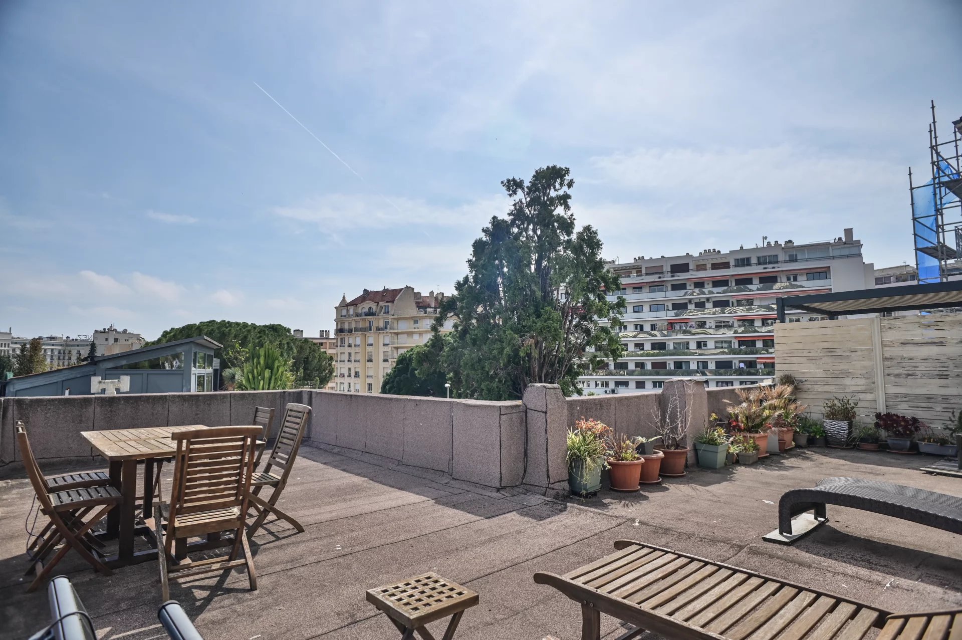 Terrace of a Belle Époque apartment in Cannes Apartment terrace in Cannes with wooden furniture and views of surrounding buildings.