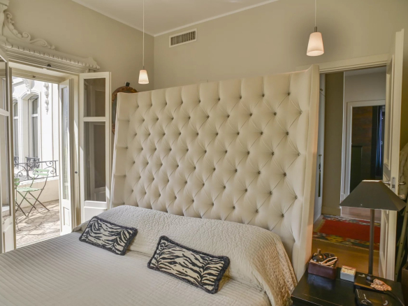 Bedroom in a Belle Époque apartment in Cannes, with a tufted bed and a balcony.