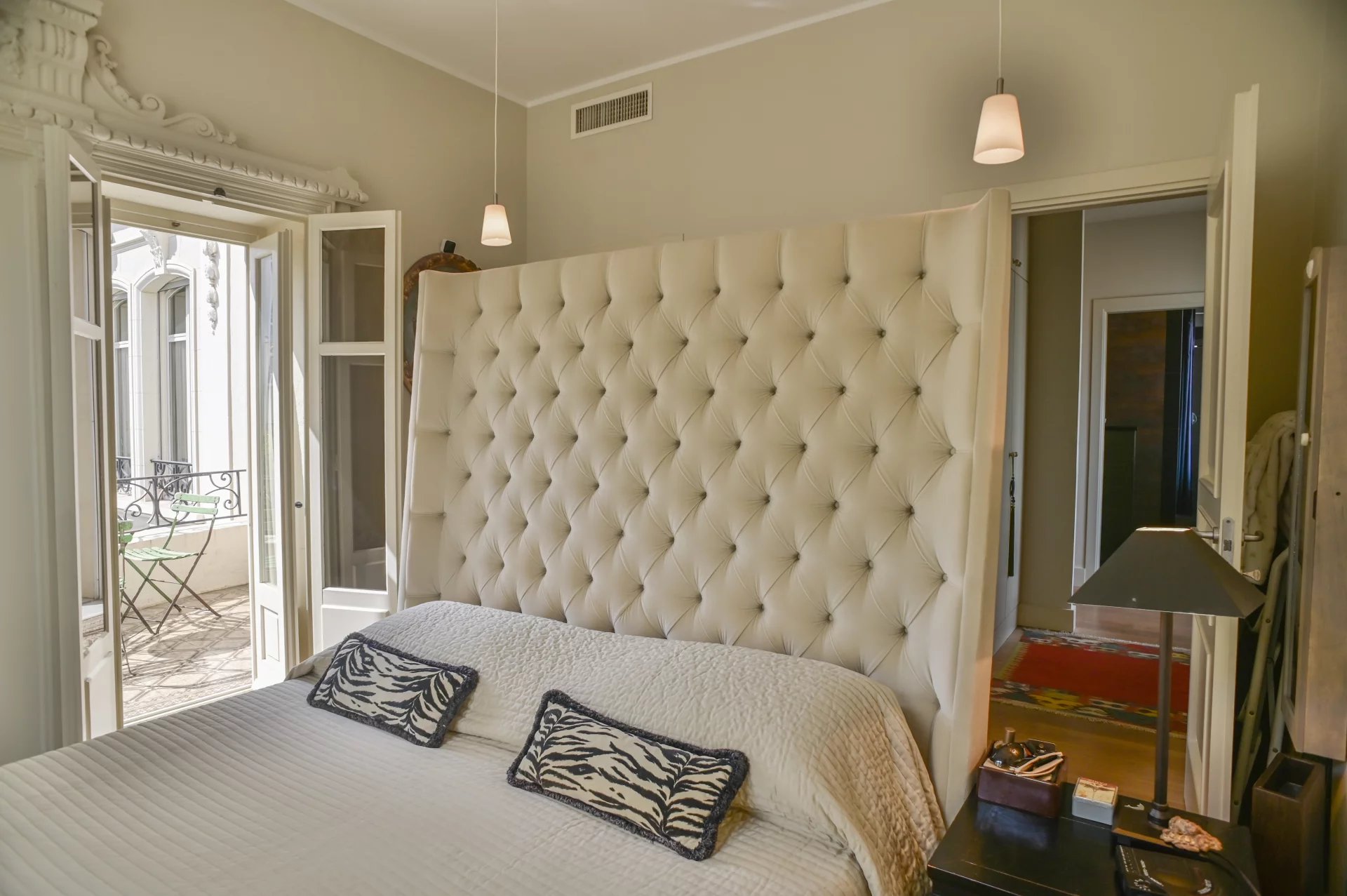 Belle Époque apartment room in Cannes Bedroom in a Belle Époque apartment in Cannes, with a tufted bed and a balcony.