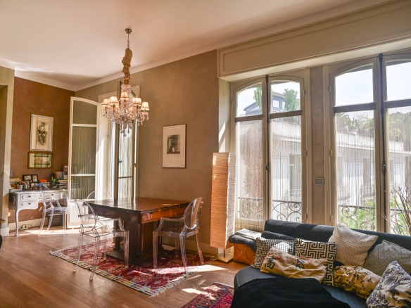 Interior of a Belle Époque apartment in Cannes, with a bright living room and a wooden dining table.
