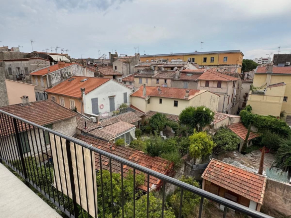 Vue depuis le balcon d'un appartement au vieux Antibes, montrant des toits de maisons et des jardins.