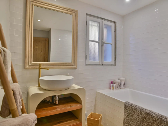 Salle de bain moderne avec baignoire et miroir, décorée de carrelage blanc.