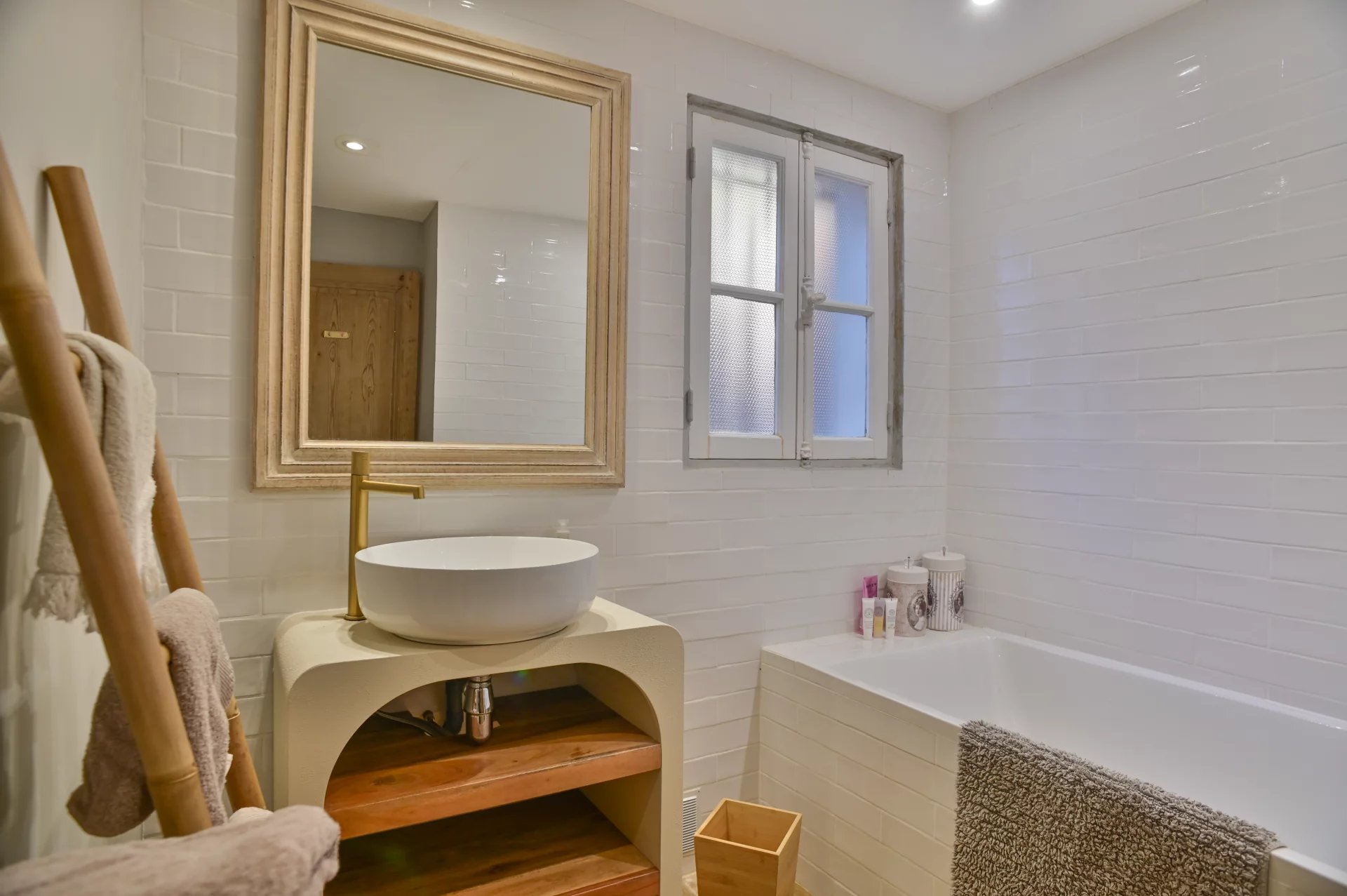 Salle de bain moderne avec baignoire et miroir, décorée de carrelage blanc.