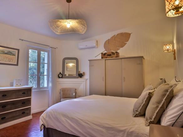 Chambre d'une propriété rénovée avec lit double et mobilier élégant, lumière naturelle.
