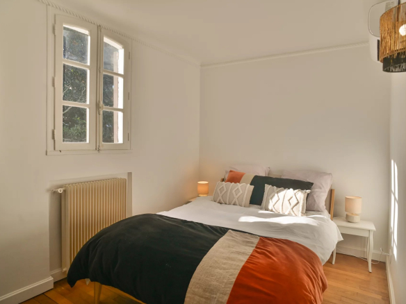 Chambre d'une propriété rénovée avec lit double et fenêtres donnant sur l'extérieur.