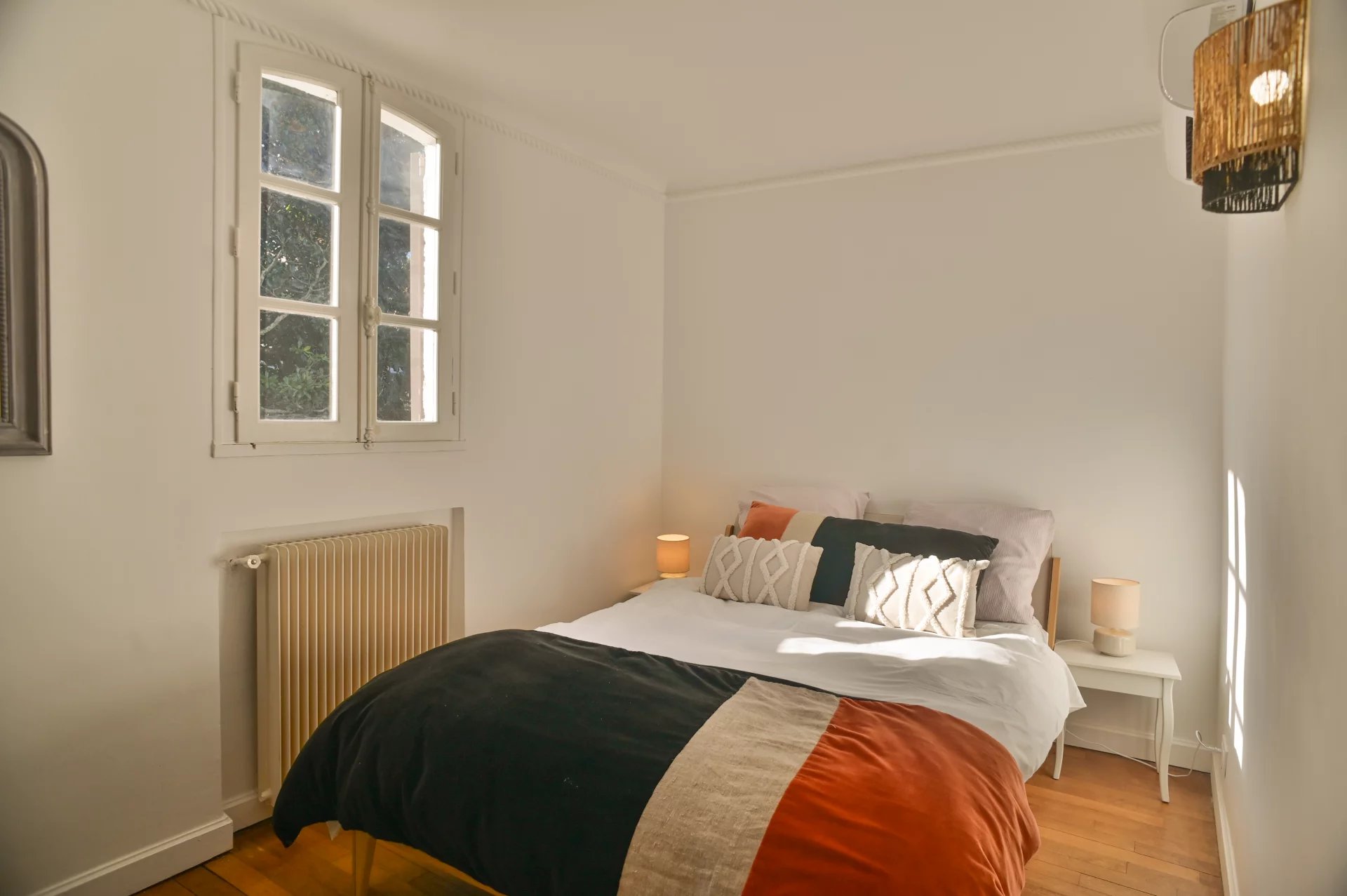 Chambre d'une propriété rénovée avec lit double et fenêtres donnant sur l'extérieur.
