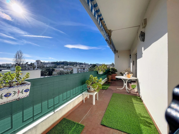 Terrasse d'un appartement à Antibes avec vue sur la mer et les montagnes, mobilier de jardin.