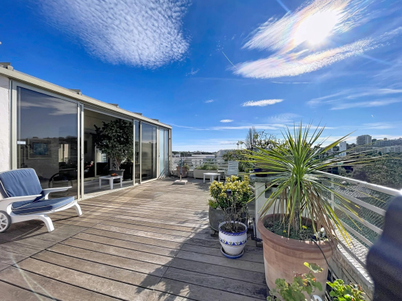 Terrasse ensoleillée d'un appartement à Antibes avec vue latérale sur la mer et montagnes.