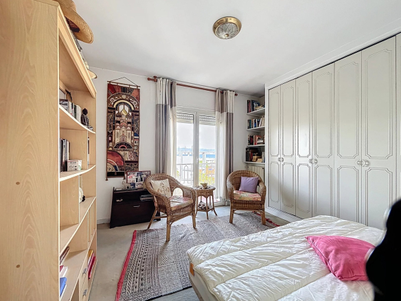 Chambre d'un appartement à Antibes avec mobilier en bois et vue sur le balcon.