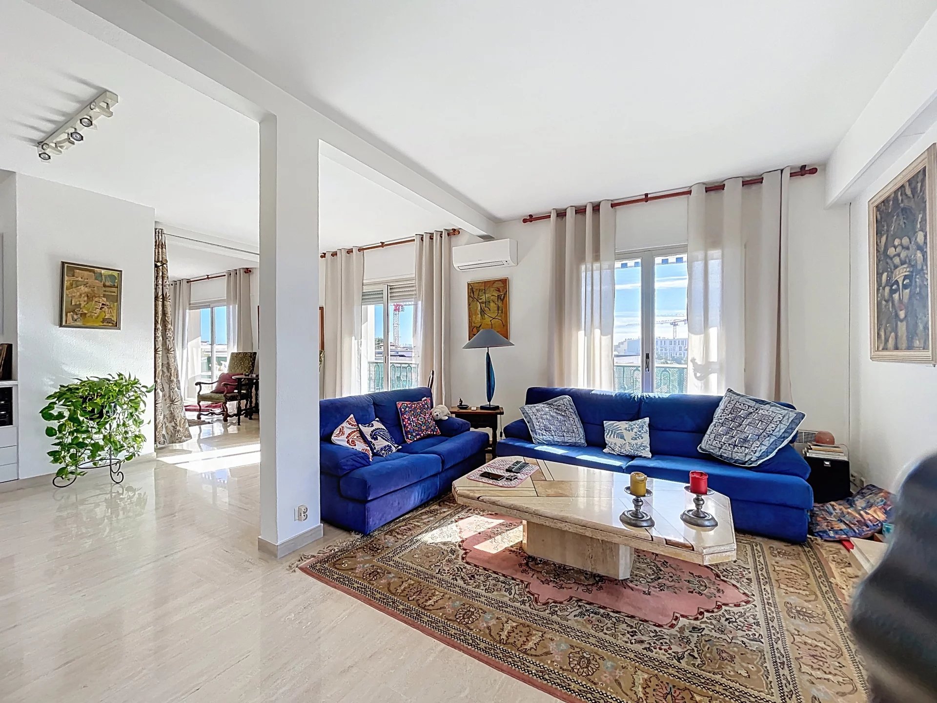 Appartement lumineux à Antibes Appartement de 154 m² à Antibes, salon lumineux avec canapé bleu et vue sur la mer.
