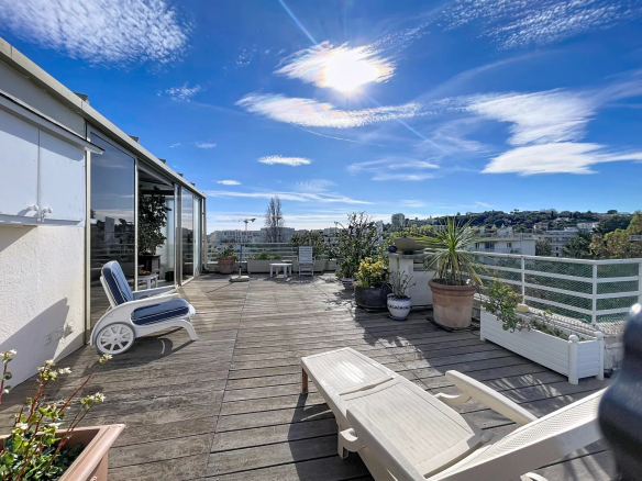 Terrasse spacieuse d'un appartement à Antibes avec vue latérale sur la mer et montagnes.