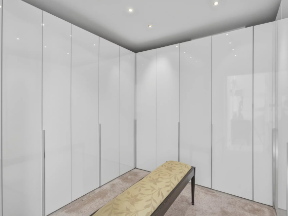Intérieur d'un appartement avec des placards blancs et un banc sur un tapis beige.