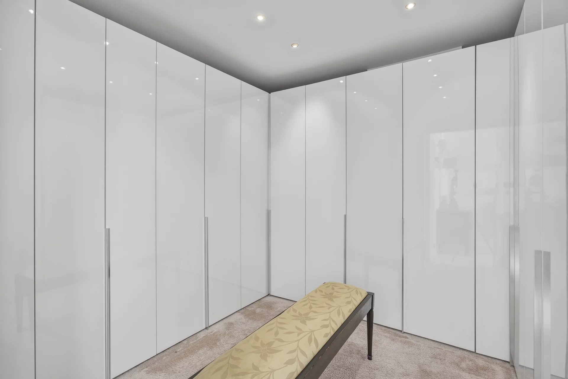Intérieur de l’appartement au Cannet Intérieur d'un appartement avec des placards blancs et un banc sur un tapis beige.