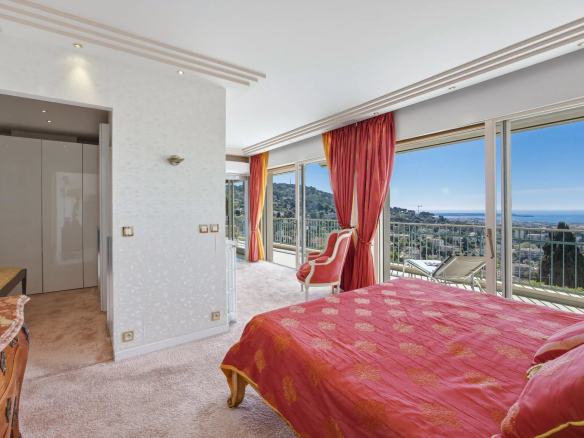 Chambre d'appartement avec vue mer, décorée avec un lit et des fenêtres panoramiques.