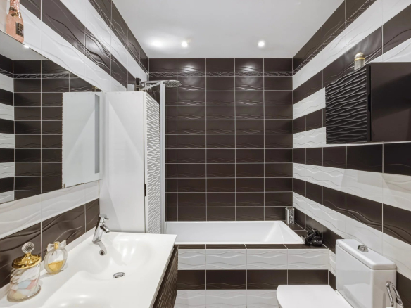 Salle de bain moderne avec baignoire, lavabo et carrelage noir et blanc.