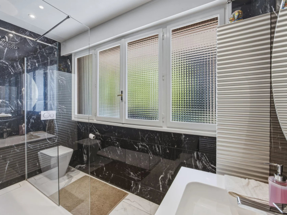 Salle de bain moderne avec douche en verre et carrelage noir et blanc.
