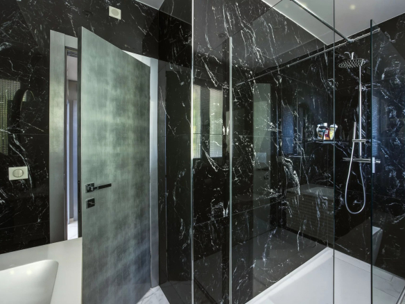 Salle de bain moderne avec douche en verre et murs en marbre noir.