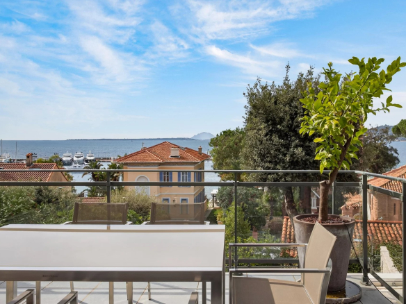 Apartment terrace with sea view in Cap d'Antibes, surrounded by houses and greenery.