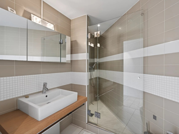 Modern bathroom with shower and wooden sink, beige and white tiles.