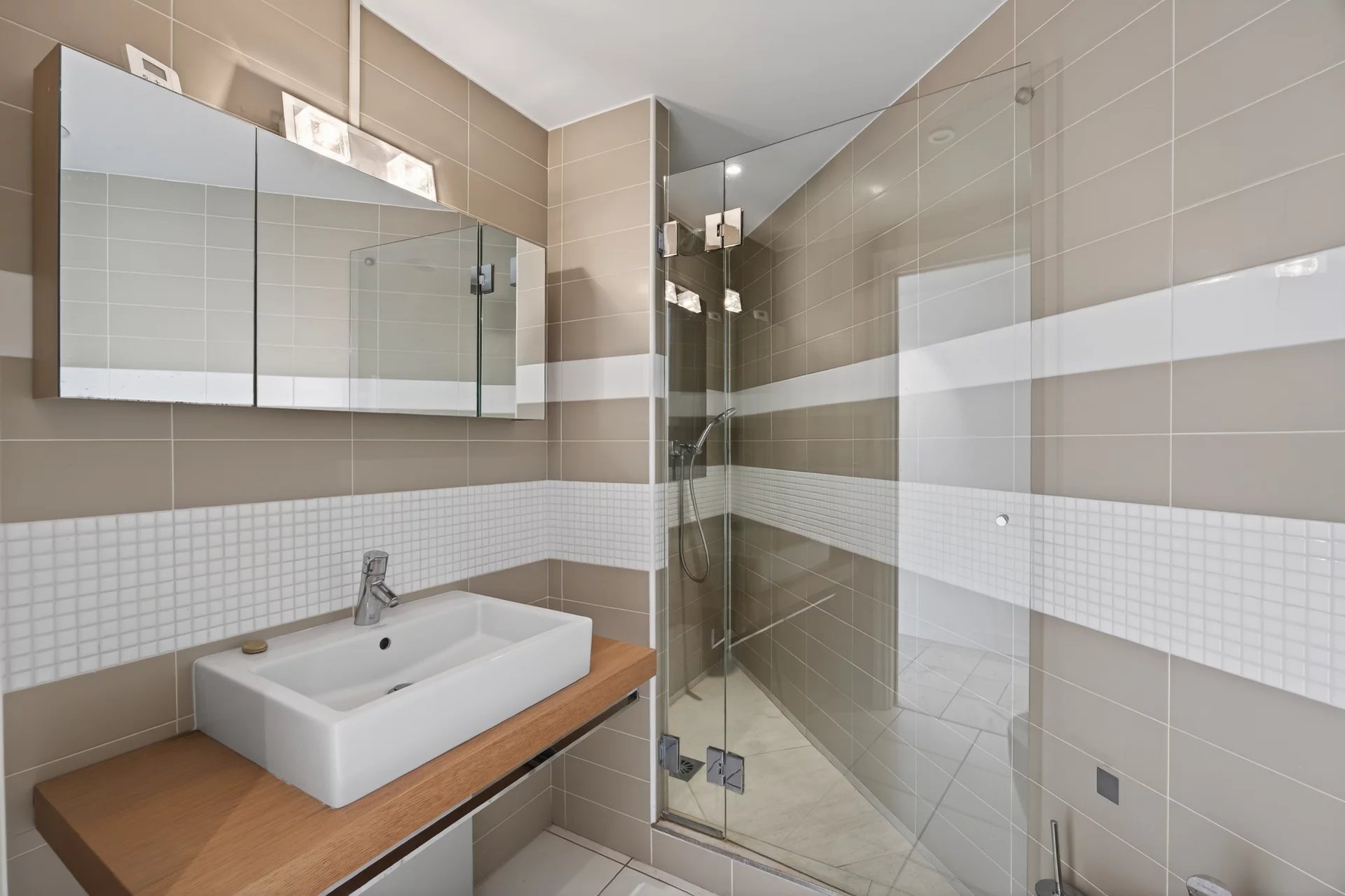 Modern bathroom in Antibes Modern bathroom with shower and wooden sink, beige and white tiles.