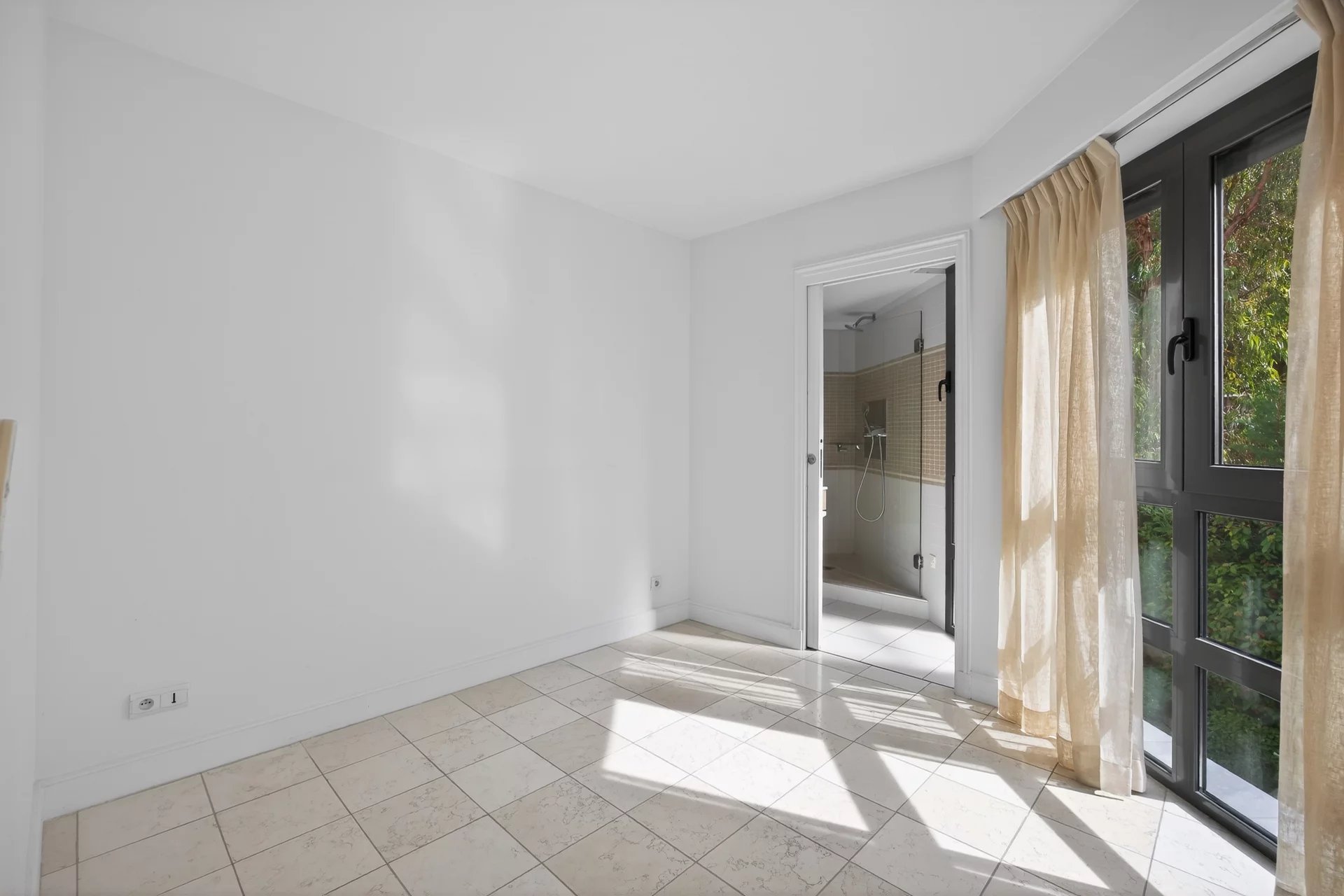 Interior of an apartment in Antibes Interior of a bright apartment with tiled floor and windows opening to the outside.