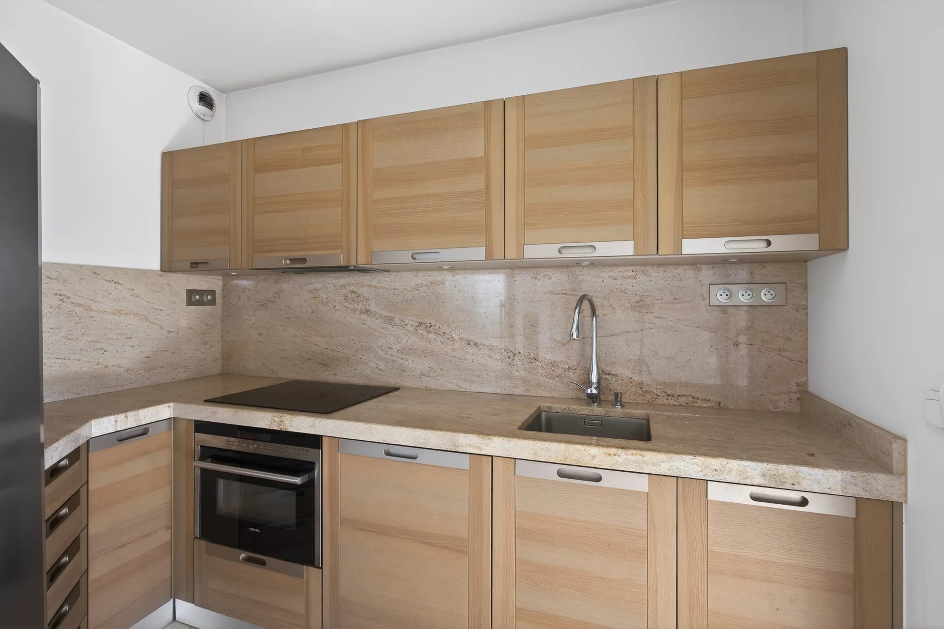Kitchen of an apartment in Antibes Modern wooden kitchen with marble worktops in an apartment in Antibes.