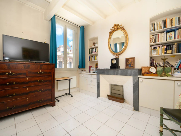 Interior of a 3-room apartment in Cannes with a wooden piece of furniture, a television and a fireplace.
